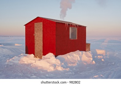 Red Ice Fishing Hut On A Frozen Lake During Winter.