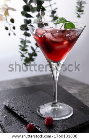 Red iced coctail with raspberry slice and liquid splash. 