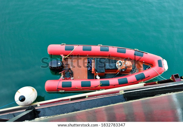 Red inflatable boat with a motor. Inflatable boat\
on the water.