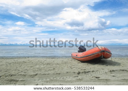 Red inflatable or rigid hulled boat on a alaskan beach 