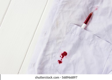 Red Ink Stain On White Shirt With Wooden Table Background 