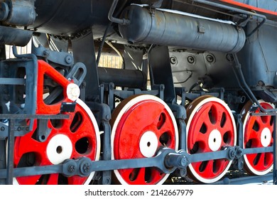Red iron wheels of an old locomotive with a steam engine close-up. Retro steam locomotive on rails. Railway train, vintage style. 