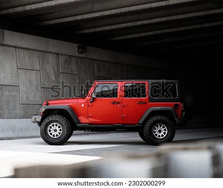 Red Jeep Wrangler under a bridge