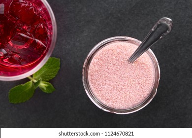 Red jelly or jello powder in jar with spoon, prepared red jelly on the side, photographed overhead on slate (Selective Focus, Focus on the jelly powder and the prepared jelly)