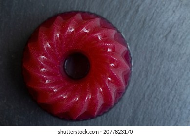 Red Jelly Texture Isolated On A Black Stone Tile . Macro Top View