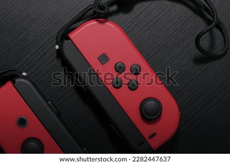Red Joycon controller on a black table. Perfect for gaming enthusiasts and Nintendo fans. This photo captures the essence of entertainment and fun.