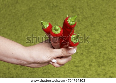 Red juicy hot pepper in a woman's hand. On a light green background.
