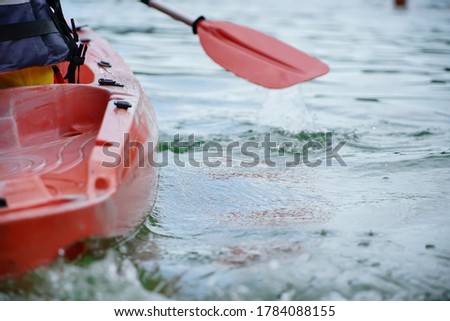 Red kayak floats on water, rear side view