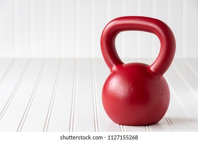 Red Kettle Bell On A White Bead Board Background
