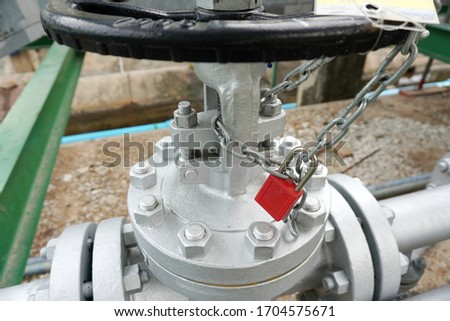 Red key lock and chain to prevent the valve being opened is part of the Lock out tag out system in oil and gas plant.