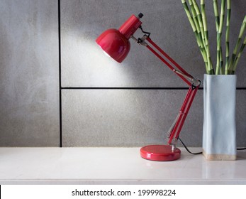 Red Lamp With Vase Of Lucky Bamboo On Desk In Modern Room