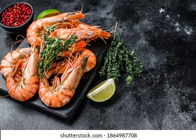 Red Langostino shrimps Prawns on a marble board.  Black background. Top view. Copy space.