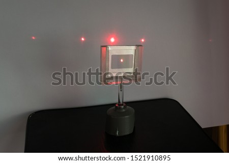 Red laser light passes through a grating, causing diffraction. Physics experiment.