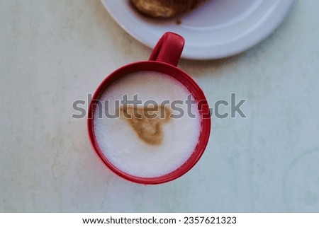 a red latte cup with a heart pattern is on the table