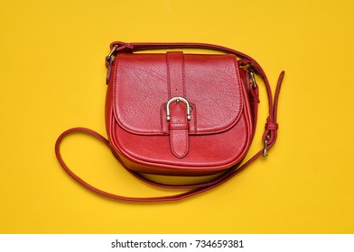 Red Leather Bag On A Long Strap On A Yellow Background. Women's Accessories. Top View.