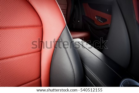 Red leather passenger seat in modern sport car, frontal view, blurred back seats in the background