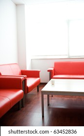 Red Leather Sofa And White Table At Waiting Room.