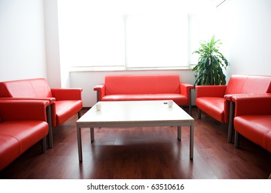 Red Leather Sofa And White Table At Waiting Room.