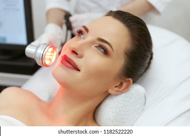 Red Led Light Treatment. Woman Doing Facial Skin Therapy 