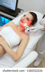 Red Led Light Treatment. Woman Doing Facial Skin Therapy 