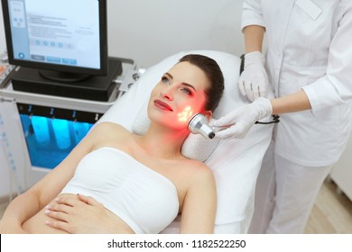 Red Led Light Treatment. Woman Doing Facial Skin Therapy 