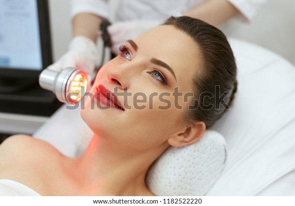 Red\
Led Light Treatment. Woman Doing Facial Skin Therapy\
