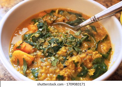 Red Lentil Curry with Sweet Potato and Spinach in a Bowl with a Spoon