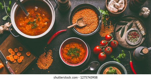 Red Lentil Soup With Cooking Ingredients On Dark Rustic Kitchen Table Background, Top View. Healthy Vegan Food Concept. Vegetarian Lentil Meal Dishes. Clean Eating. 