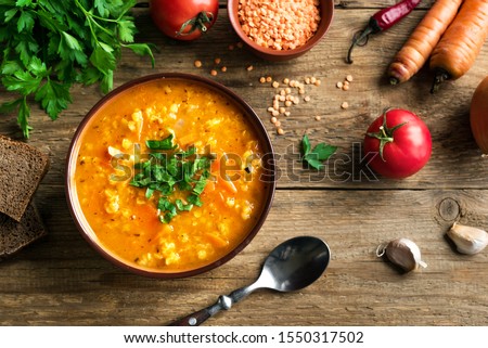 Red Lentil Soup with ingredients on wooden background, top view, copy space. Traditional turkish or arabic lentil and vegetable spicy soup, healthy vegan food.