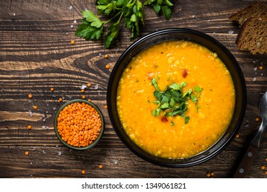 Red Lentil Soup Puree In Black Plate On Wooden Table. Top View With Copy Space.