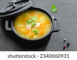 Red lentil vegetable soup in cast iron pot on dark background. Top view, copy space, flat lay.