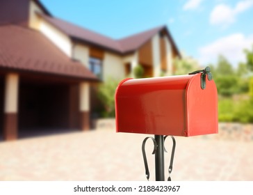 Red Letter Box And Blurred View Of Modern House On Sunny Day