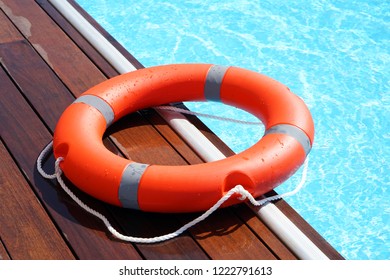 The red life ring lies on the wooden floor of the swimming pool. Life cycle, floating above the sunny blue water. Ring of life in the pool - Shutterstock ID 1222791613