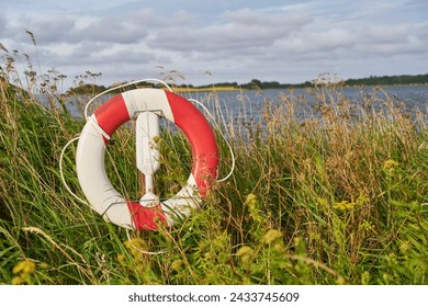 Red lifebuoy as flotation device on waterfront near lake for safety - Powered by Shutterstock