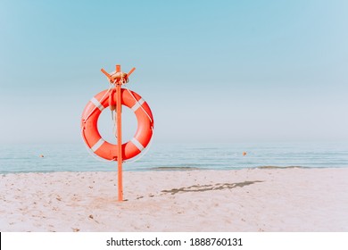 red lifebuoy on a sandy beach. Red lifebuoy on a sandy beach shore on a sunny day.