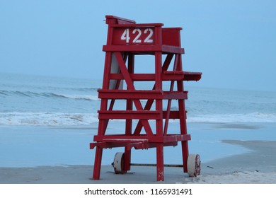 Red lifeguard chair tower on quiet beach at sunrise or sunset.  - Powered by Shutterstock