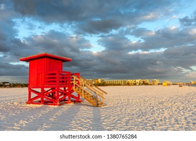 Red lifeguard tower under a dramatic, cloud filled sky.