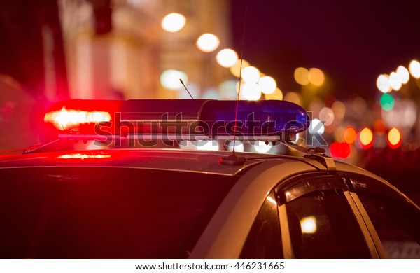Red light flasher atop of a police car. City lights on\
the background. 