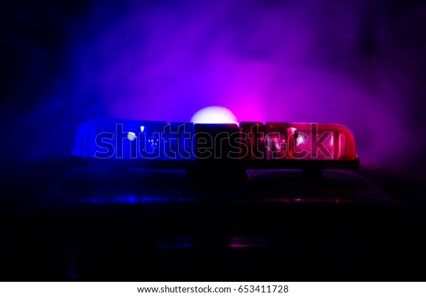 Red light flasher atop of a police car. City\
lights on the background.