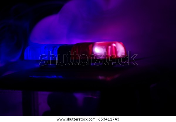 Red light flasher atop of a police car. City
lights on the background.