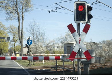 Red light of the railway crossing and lowered barrier blocking the passage. High quality photo