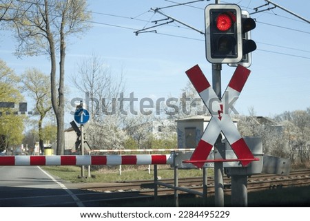 Red light of the railway crossing and lowered barrier blocking the passage. High quality photo