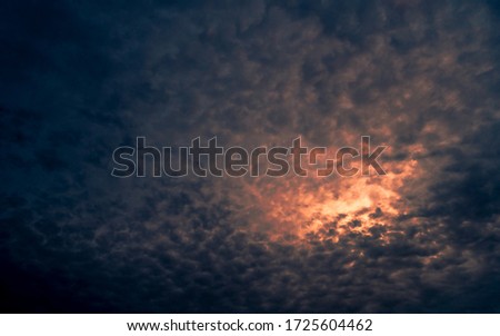 Red light of sun in dark cloudy sunset sky. Dramatic sky with beautiful pattern of fluffy clouds. Mental power or psychic power background. Power of nature. Exotic cloudscape. Climate change concept.