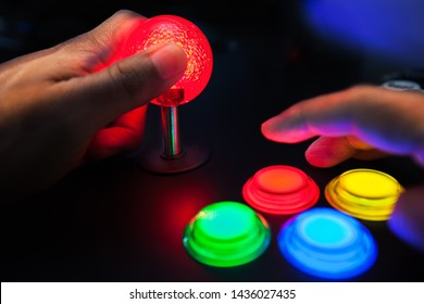 A Red Lighted Arcade Joystick And Four Button Layout Push Buttons Being Played By A Video Gamer On A Retro Arcade Machine.