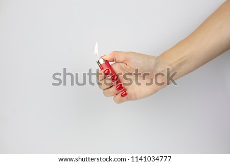 red lighter with fire in woman's hand with red nails isolated on white background