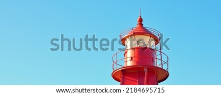 Red lighthouse against clear blue sky, close-up. Denmark, Europe. Travel destinations, landmark, navigation, sea, symbol of hope and peace, graphic resources