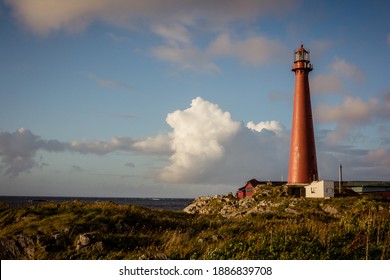 Red lighthouse of Andenes in the Vesteralen Islands archipelago in Northern Norway, green grass and blue sky