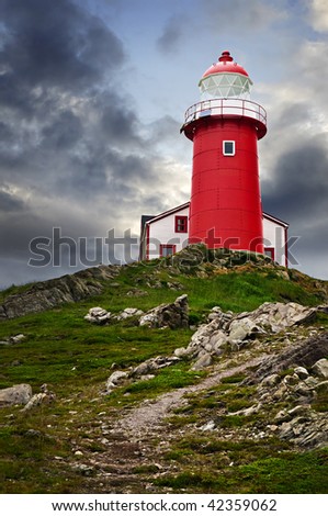 Red lighthouse on hill against stormy sky in Ferryland Newfoundland