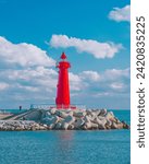 A red lighthouse stands guard under a blue sky along Busan