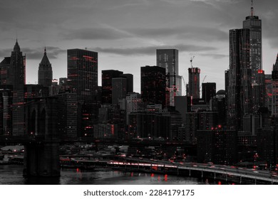 Red lights shining in black and white night time cityscape with the Brooklyn Bridge and buildings of Manhattan in New York City NYC